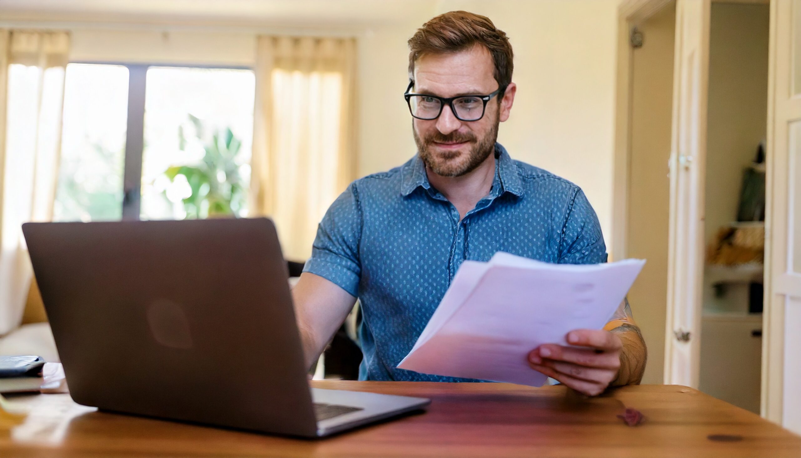 imagem de um morador na frente do computador segurando papeis